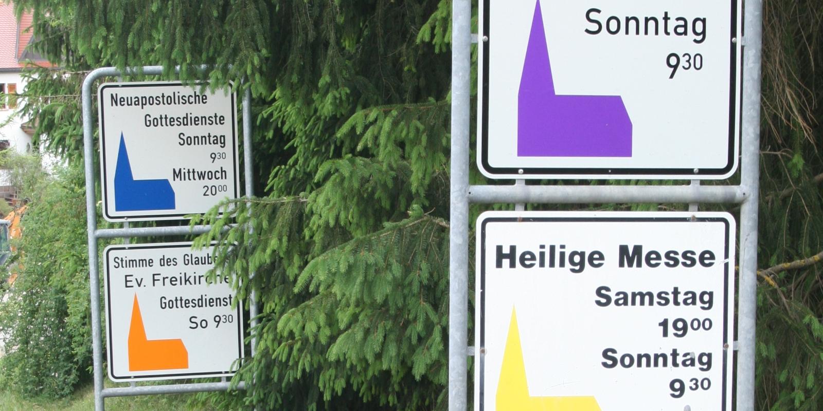 Hinweistafeln am Ortseingang mit  Gottesdienstzeiten der verschiedenen Konfessionen  Der Begriff ist im Christentum entstanden und bezeichnet in der christlichen Theologie ursprünglich eine Zusammenfassung von Glaubenssätzen. Daher wird der Begriff auch als Bezeichnung für eine christliche Richtung verwendet, die sich durch ein gemeinsames Bekenntnis von anderen christlichen Richtungen unterscheidet, und im weiteren Sinn auch allgemein für christliche Richtungen; der Begriff bezeichnet heute also die unterschiedlichen christlichen Kirchen und Gruppierungen. Ex-Bild-DB-ID: 10902